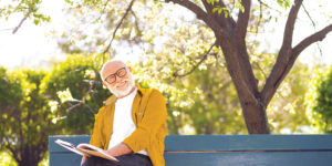 Happy older man reading outside, enjoying cognitive and mental benefits