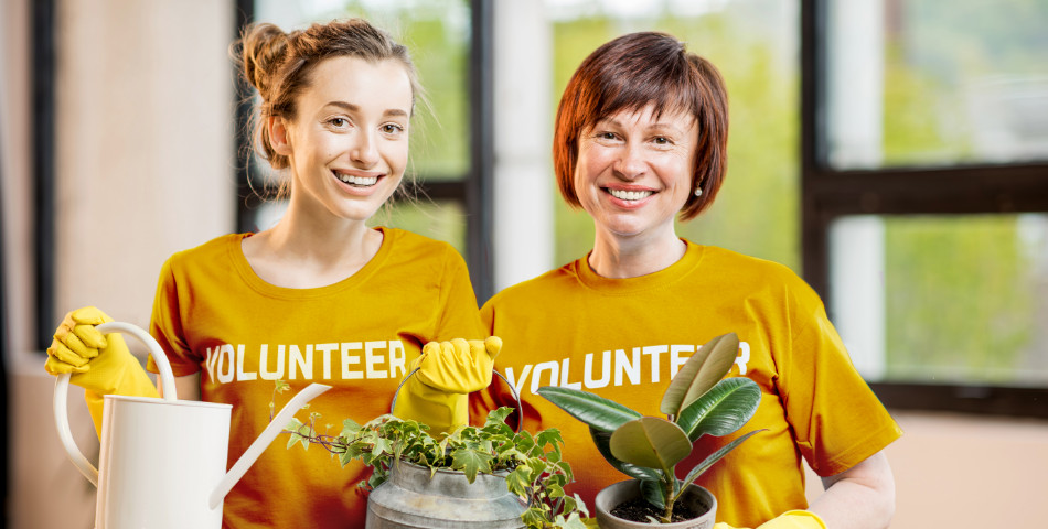 Older woman smiles with a fellow volunteer taking care of plants